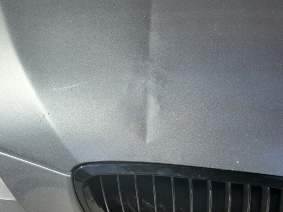 Clear coat cracked on a BMW hood after a dent was forced with the wrong tool