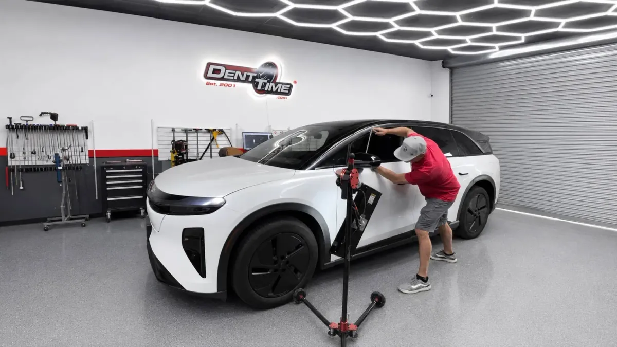 A Dent Time technician repairing a white SUV inside the Dent Time shop in Escondido