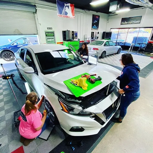 Students working real vehicles during paintless dent repair training at the Dent Time shop in Escondido