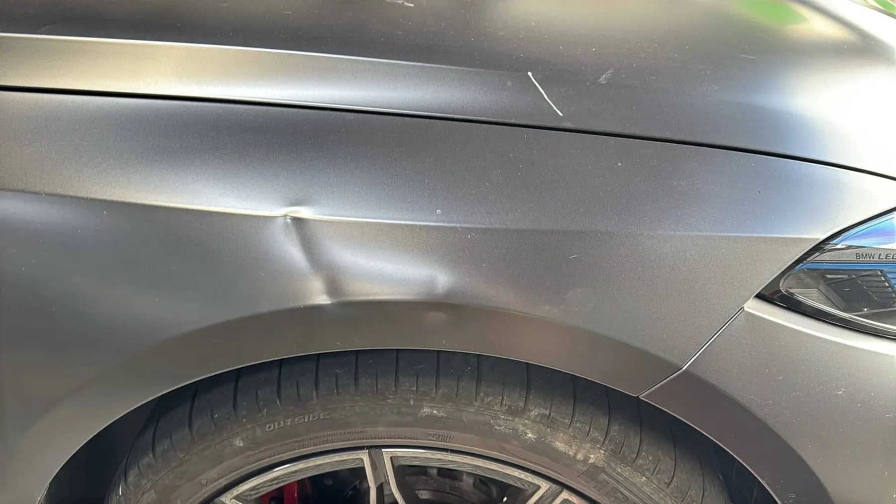 Sharp crease across a BMW fender body line before repair