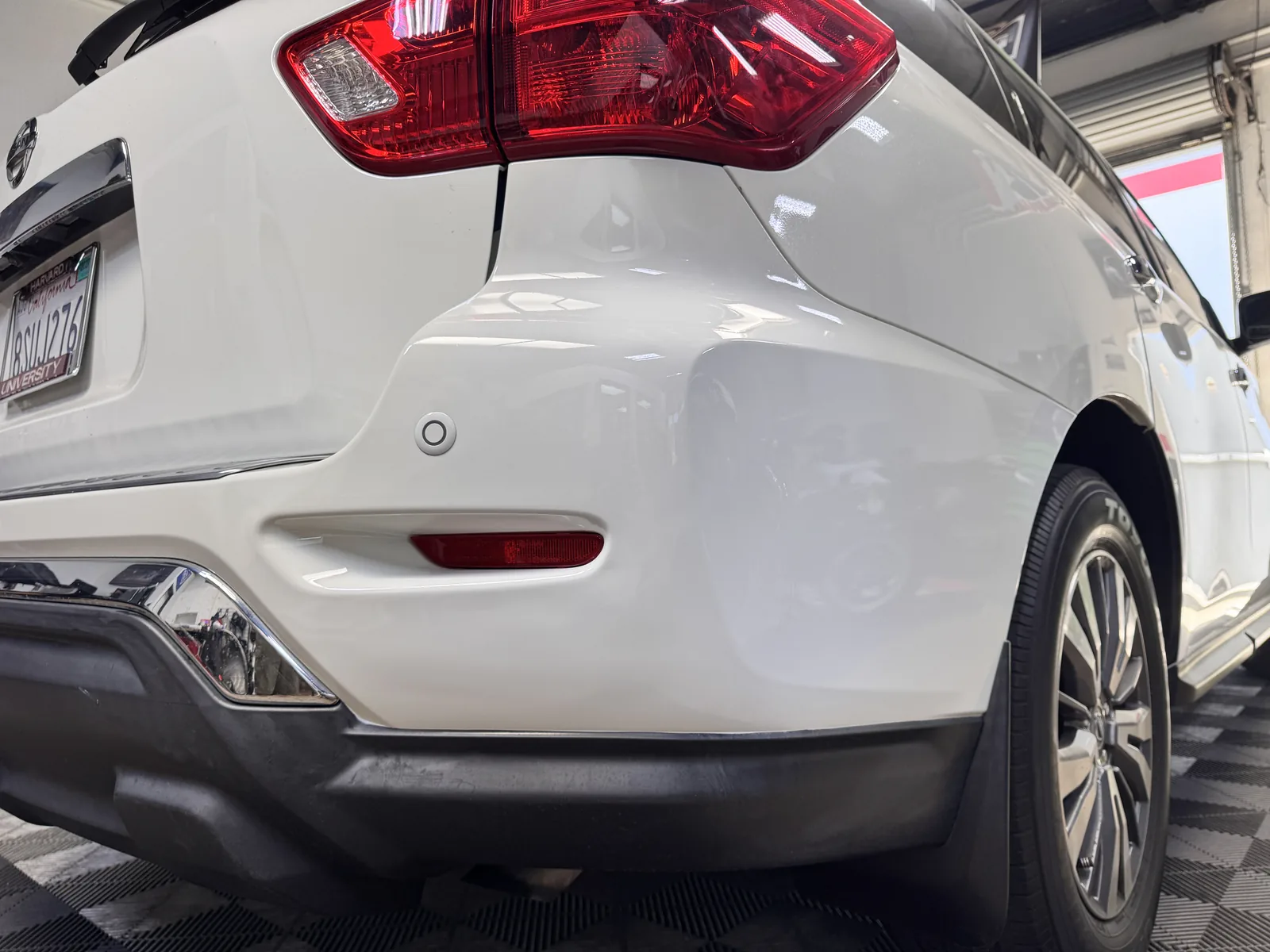 The same Nissan rear bumper corner after the dent was worked out and the scuffs buffed, no repaint