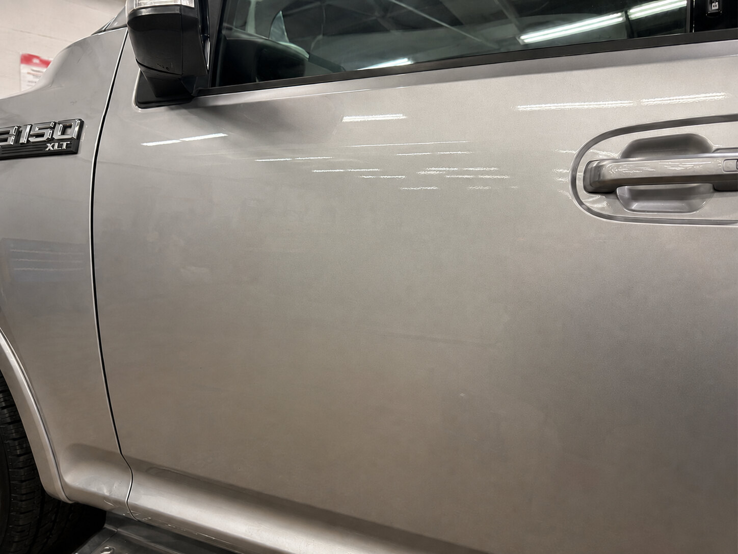 A truck door after paintless dent repair, the crease gone and the factory paint untouched