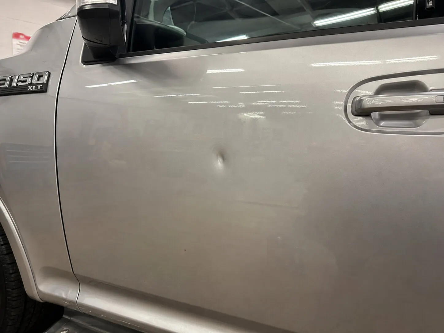 Sharp focused dent in a Ford F-150 door before repair