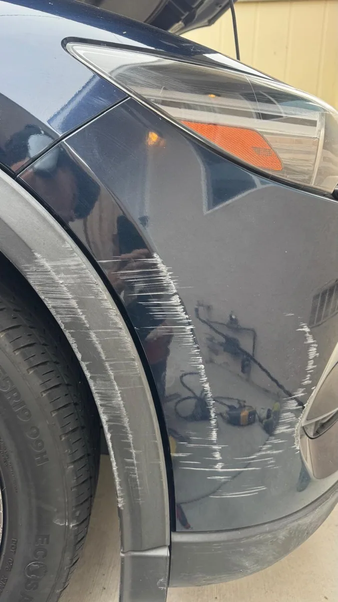 Deep scrape across the front fender and wheel arch trim of a dark blue SUV before repair in Escondido