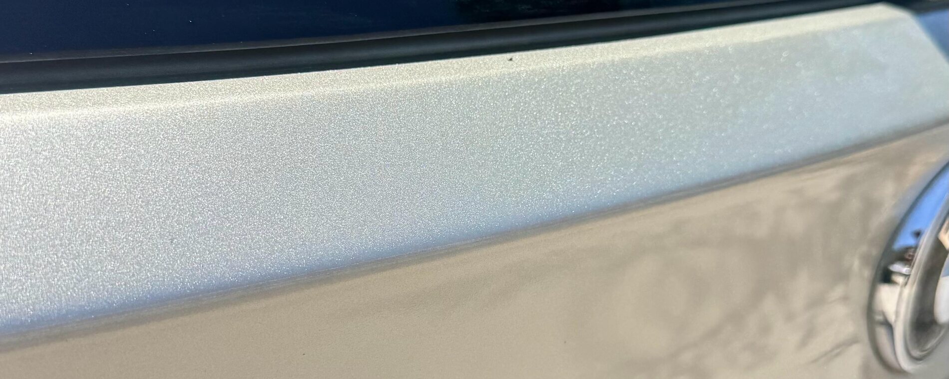 A sharp crease pressed across a painted tailgate before paintless dent repair