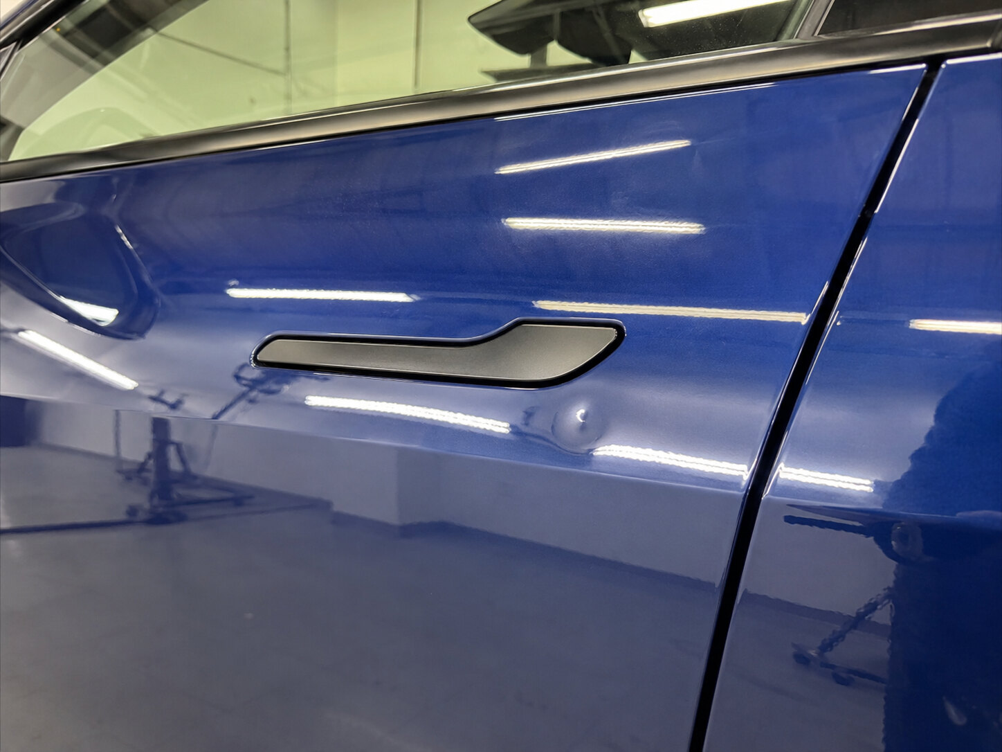 A dent in a Tesla aluminum door before repair
