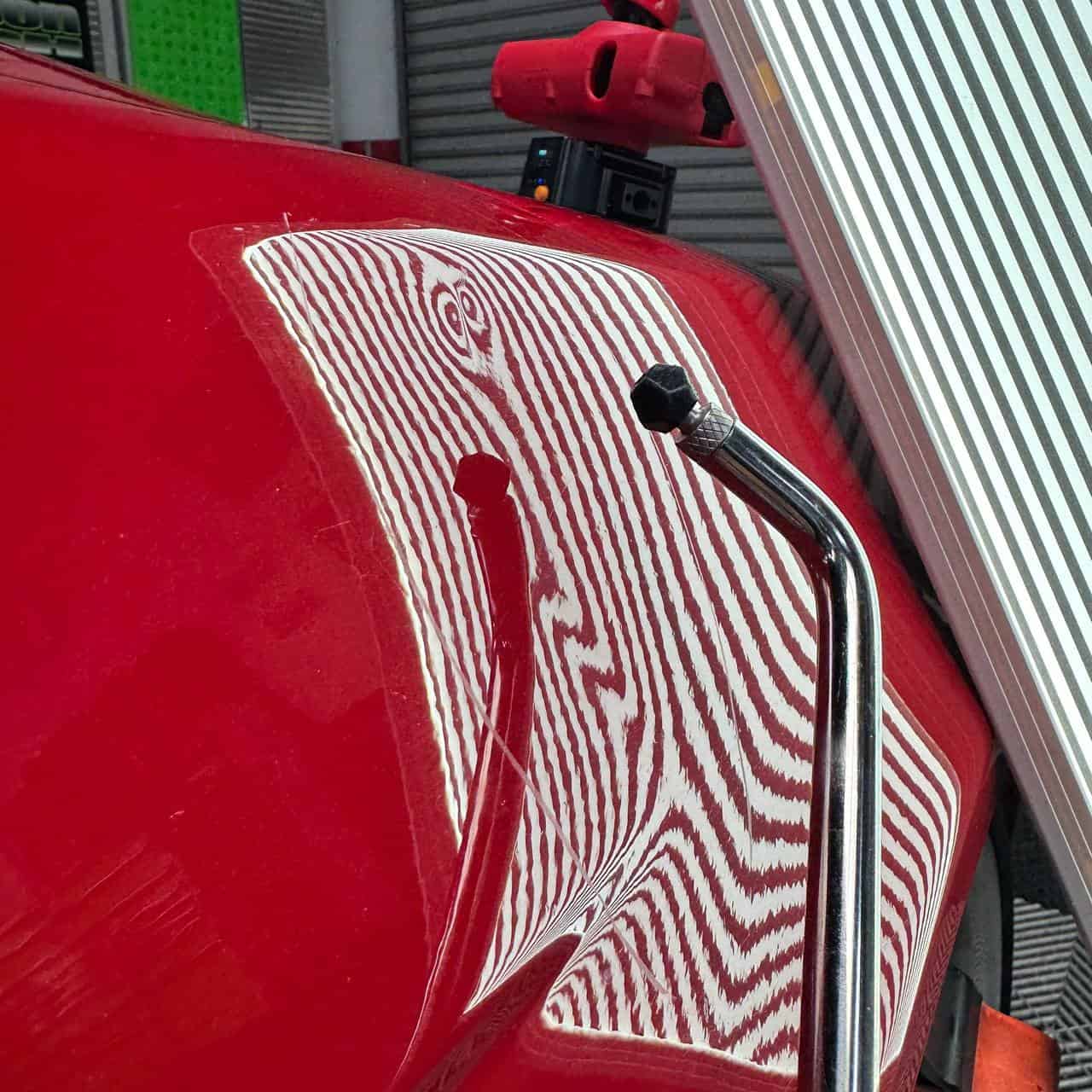 PDR tool repairing BMW M5 fender dent with line board San Diego